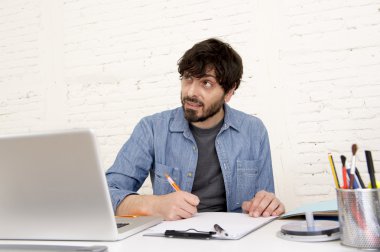 Genç İspanyol hippi iş adamı bilgisayar bürosunda çalışıyor.