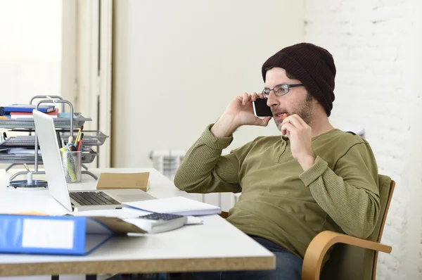 Young attractive hipster businessman working from home office with mobile phone — Stockfoto