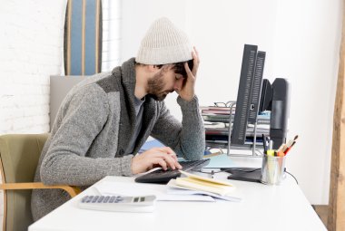 young worried businessman in cool hipster beanie look looking desperate having problem working in stress