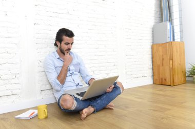 young man in hipster modern casual style look sitting on living room home floor working on laptop 