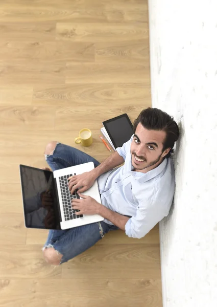 Young man in hipster modern casual style look sitting on living room home floor working on laptop — Zdjęcie stockowe