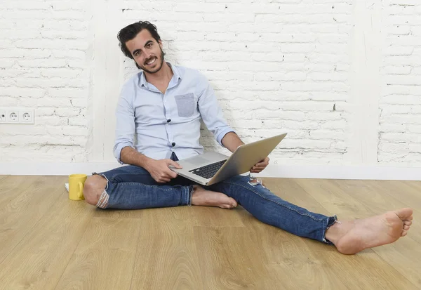 Young man in hipster modern casual style look sitting on living room home floor working on laptop — Zdjęcie stockowe