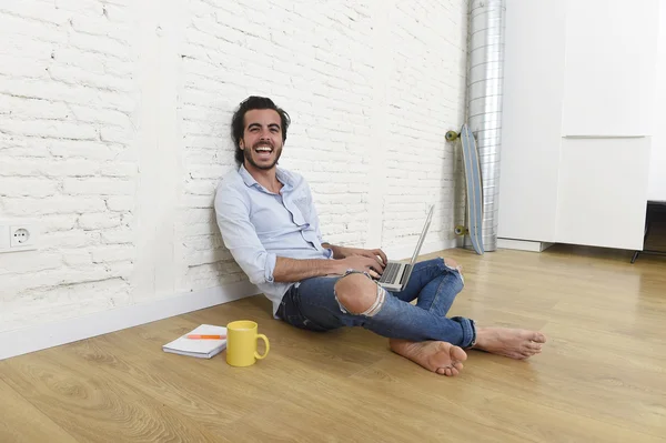 Young man in hipster modern casual style look sitting on living room home floor working on laptop — Stock fotografie