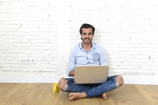 Young man in hipster modern casual style look sitting on living room home floor working on laptop — Stok fotoğraf