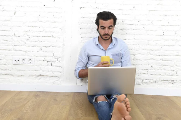 Giovane in stile moderno hipster casual look seduto sul pavimento della casa soggiorno di lavoro sul computer portatile — Foto Stock