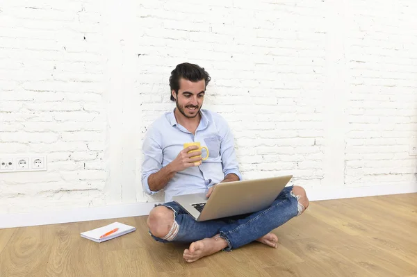 Young man in hipster modern casual style look sitting on living room home floor working on laptop — Zdjęcie stockowe