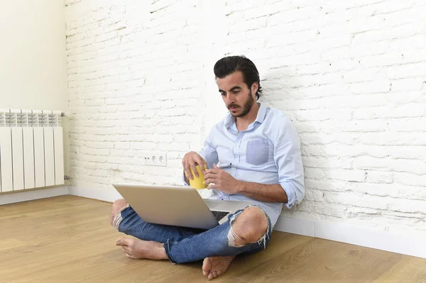 Young man in hipster modern casual style look sitting on living room home floor working on laptop — Zdjęcie stockowe