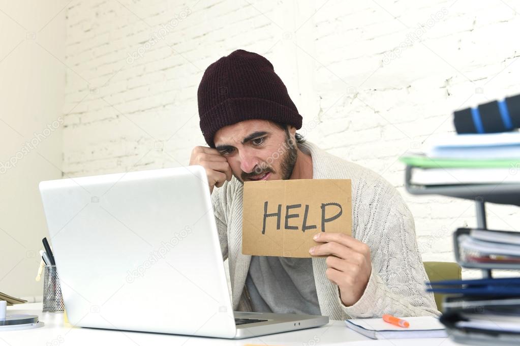 worried businessman in cool hipster beanie look holding help sign working in stress at home office