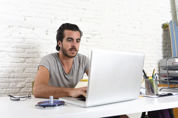 Joven moderno estilo hipster estudiante o hombre de negocios que trabaja con el ordenador portátil en la oficina en casa — Foto de Stock