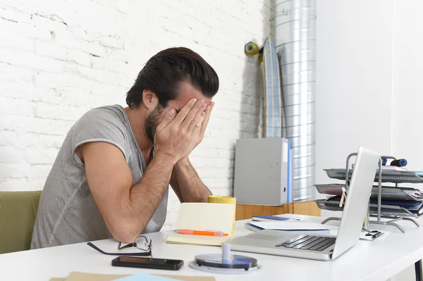 Worried student or businessman at computer covering his face with his hands depressed and sad — Stockfoto