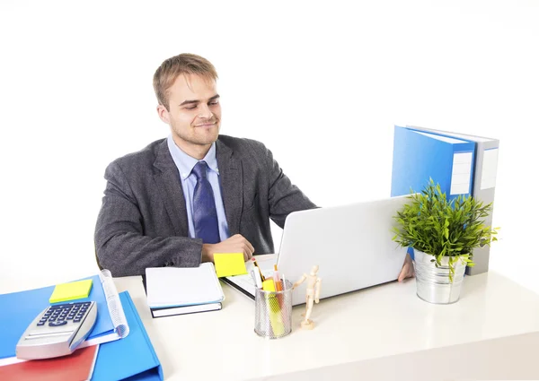 Junger attraktiver Geschäftsmann, der am Schreibtisch mit Laptop beschäftigt ist und zufrieden lächelt — Stockfoto