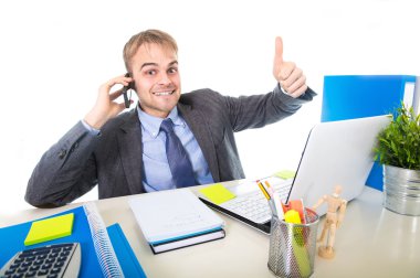 Kendine güvenen cep telefonu üzerinde ofis bilgisayar masası konuşurken gülümseyen genç mutlu işadamı