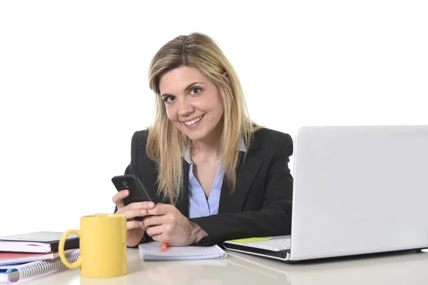 Happy Caucasian blond business woman working using mobile phone at office computer desk Stock Image