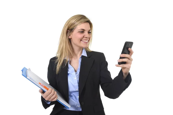 Jovem bela mulher de negócios cabelo loiro usando o aplicativo de internet no telefone celular segurando pasta de escritório e caneta sorrindo feliz — Fotografia de Stock