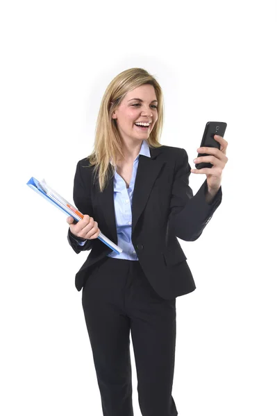 Jovem bela mulher de negócios cabelo loiro usando o aplicativo de internet no telefone celular segurando pasta de escritório e caneta sorrindo feliz — Fotografia de Stock