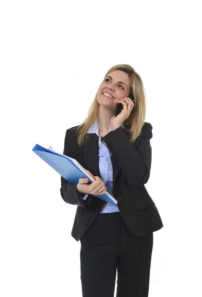 Blond hair businesswoman talking on mobile phone holding office folder and pen smiling happy Stock Picture