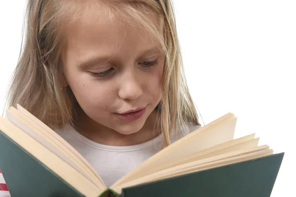 Молода солодка маленька 6 або 7 років зі світлим волоссям дівчина читає книгу, яка виглядає цікаво і захоплююче — стокове фото