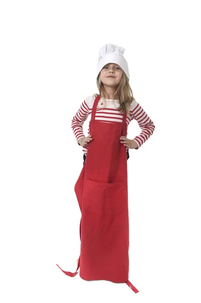 Dziewczynka w ponadgabarytowych gotowanie kapelusz i czerwony fartuch gra kucharz uśmiechnięty szczęśliwy i zabawny — Zdjęcie stockowe