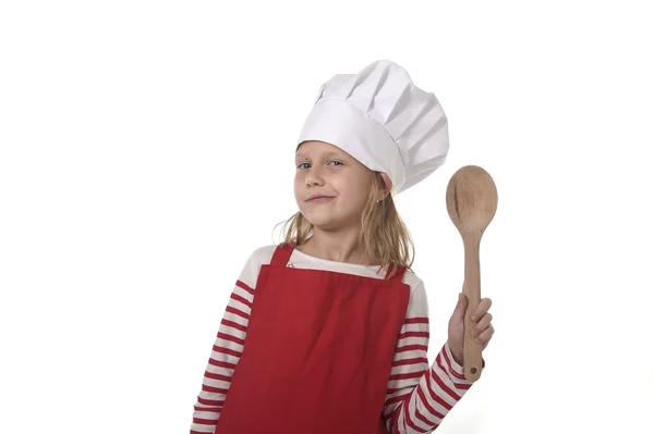 7 years old little girl in cooking hat and red apron playing cook smiling  happy holding spoon — Stock Photo, Image