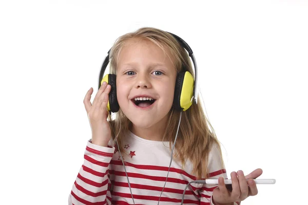 Słodkie dziewczynki z blond włosami słuchanie muzyki z słuchawek i telefonu komórkowego śpiew i taniec szczęśliwy — Zdjęcie stockowe