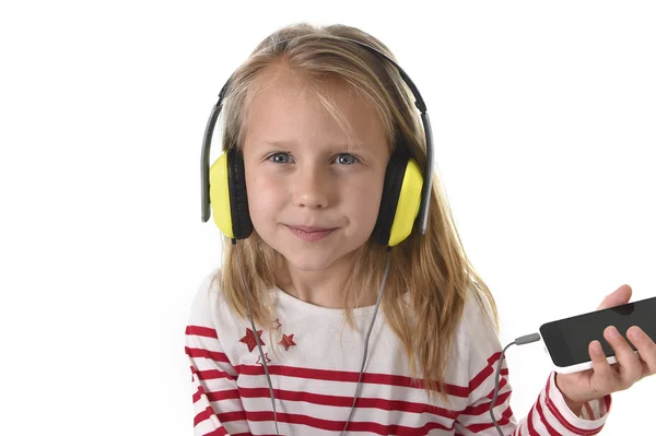 Lief klein meisje met blonde haren, luisteren naar muziek met hoofdtelefoons en mobiele telefoon gelukkig — Stockfoto