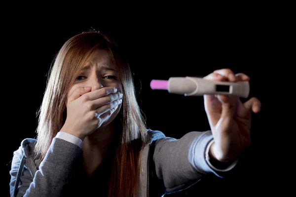 Young woman scared and shocked holding pregnancy test positive result looking unhappy — Stock Photo, Image