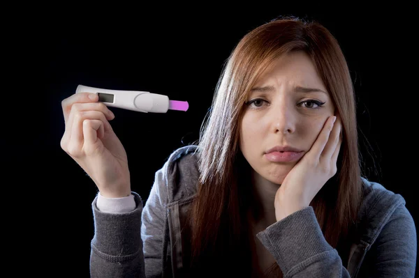 Mujer joven asustada y sorprendida sosteniendo prueba de embarazo resultado positivo buscando infeliz —  Fotos de Stock