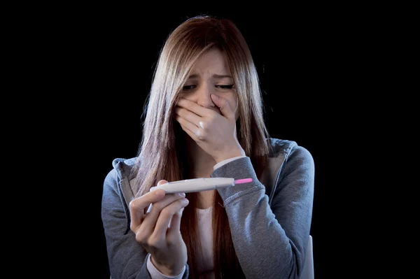 Młoda kobieta, przestraszony i szoku, trzymając ciąży test pozytywny wynik wyglądający zadowolony — Zdjęcie stockowe