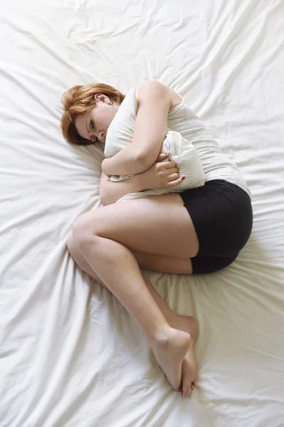 Young beautiful woman suffering stomach cramps on belly holding tummy with her hands in period pain — 图库照片