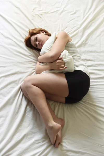 Young beautiful woman suffering stomach cramps on belly holding tummy with her hands in period pain — Stok fotoğraf