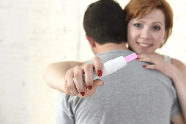Jovem mulher feliz abraçando marido segurando resultado positivo teste de gravidez esperando um bebê — Fotografia de Stock