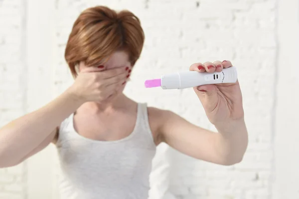 Mulher grávida segurando rosa positivo teste de gravidez cobrindo seus olhos com a mão — Fotografia de Stock