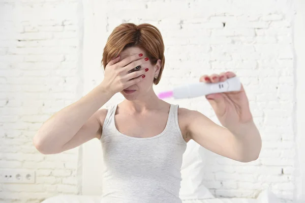 Mulher grávida segurando rosa positivo teste de gravidez cobrindo seus olhos com a mão — Fotografia de Stock