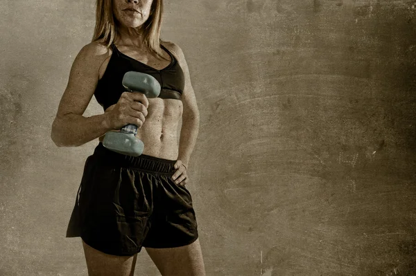 Anónimo en forma y fuerte deporte mujer sosteniendo peso en su mano posando desafiante en actitud fresca —  Fotos de Stock