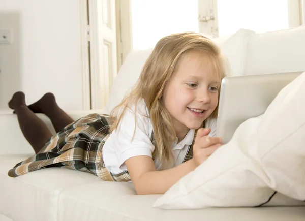 Sweet child lying on home sofa couch using internet app on digital tablet pad — Stock Photo, Image