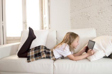 dijital tablet ped dijital tablet ped üzerinde internet uygulaması kullanarak ev kanepede yatan sarışın küçük kız