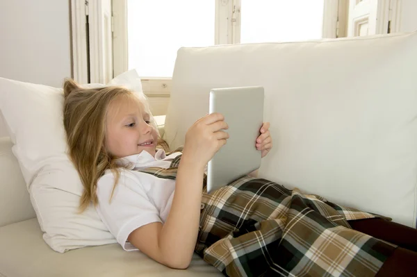 Menina loira deitada no sofá-cama em casa usando o aplicativo de internet no tablet pad digital no tablet pad digital — Fotografia de Stock
