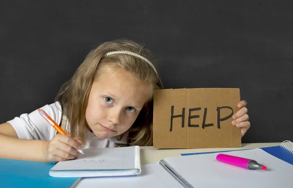 Уставшая милая младшая школьница со светлыми волосами, сидящая в стрессе и делающая домашнюю работу. — стоковое фото