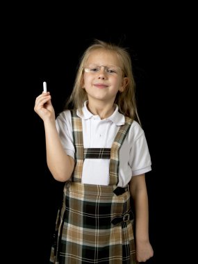 young sweet junior schoolgirl with blonde hair standing happy and smiling holding chalk