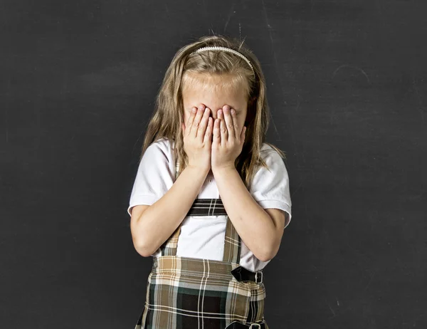 Sweet junior schoolgirl with blonde hair crying sad and shy in front of school class blackboard — Stock Photo, Image