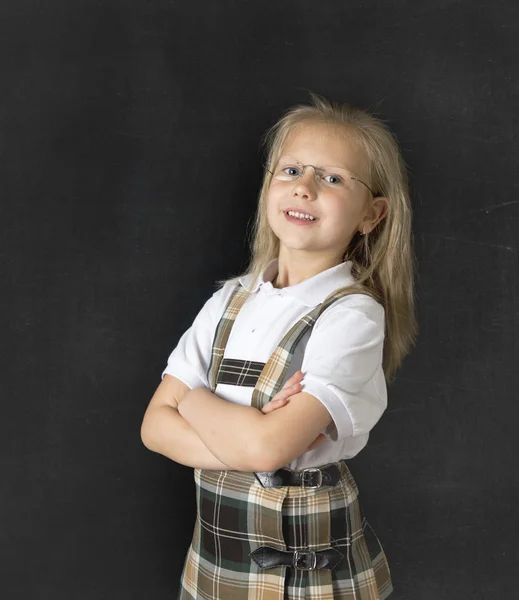 Doce júnior estudante com loira cabelo de pé e sorrindo feliz isolado no blackboard fundo — Fotografia de Stock