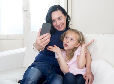selfie fotoğrafta cep telefonu ile küçük şirin sarışın kızı olan mutlu kadın