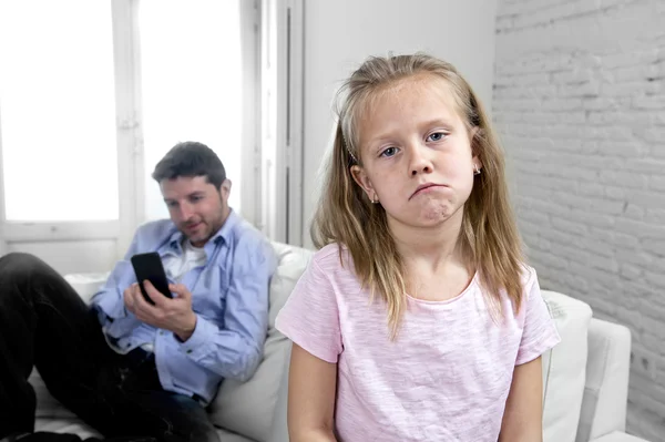 Интернет-наркоман отец с помощью мобильного телефона игнорируя маленькую грустную дочь скучно одиноким и депрессивным — стоковое фото
