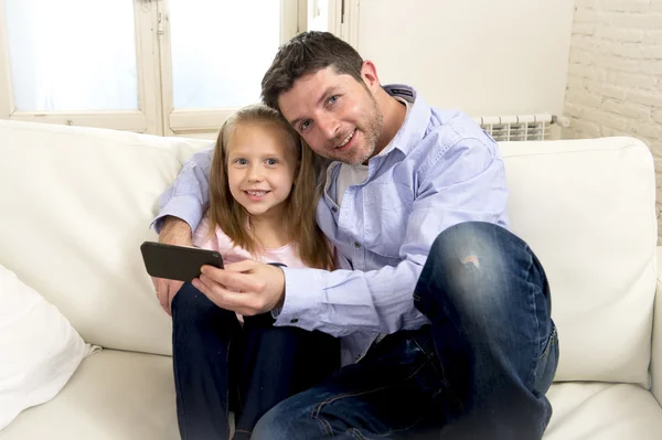 Jeune père heureux montrant douce petite fille en utilisant Internet sur téléphone mobile s'amuser ensemble — Photo