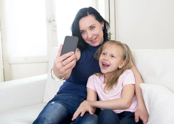 Jovem mulher feliz com sua pequena filha loira bonito tirar foto selfie com telefone celular — Fotografia de Stock