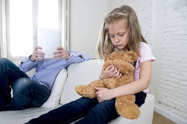 Adicto a internet padre usando tableta digital haciendo caso omiso de la pequeña hija triste aburrido abrazo osito de peluche — Foto de Stock