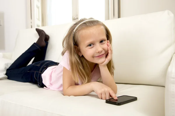 Menina loira feliz em casa sofá usando o aplicativo de internet no telefone móvel — Fotografia de Stock