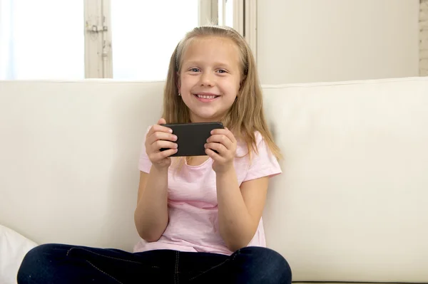 Menina loira feliz em casa sofá usando o aplicativo de internet no telefone móvel — Fotografia de Stock