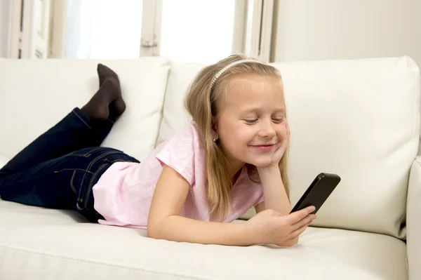 Menina loira feliz em casa sofá usando o aplicativo de internet no telefone móvel — Fotografia de Stock