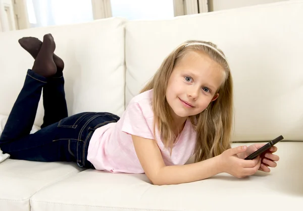 Menina loira feliz em casa sofá usando o aplicativo de internet no telefone móvel — Fotografia de Stock